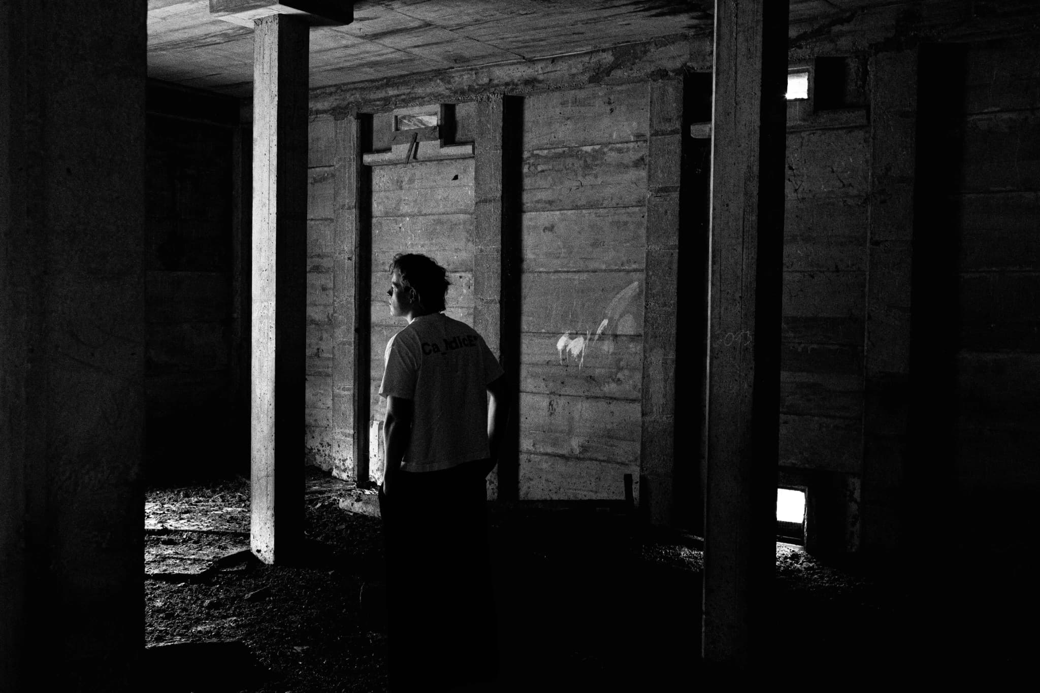 Sunday standing between concrete columns in a dark building
